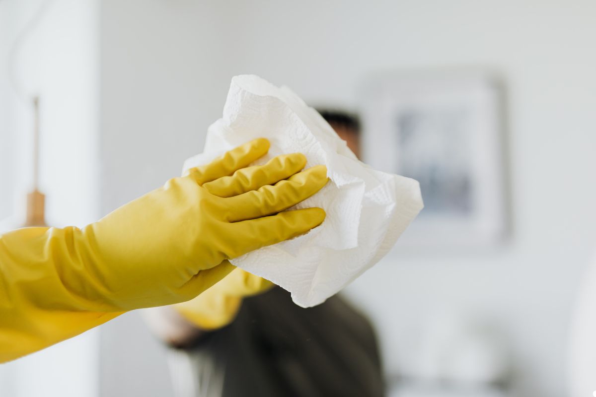 A person in yellow gloves holds a piece of paper, focusing on the document with a neutral expression.