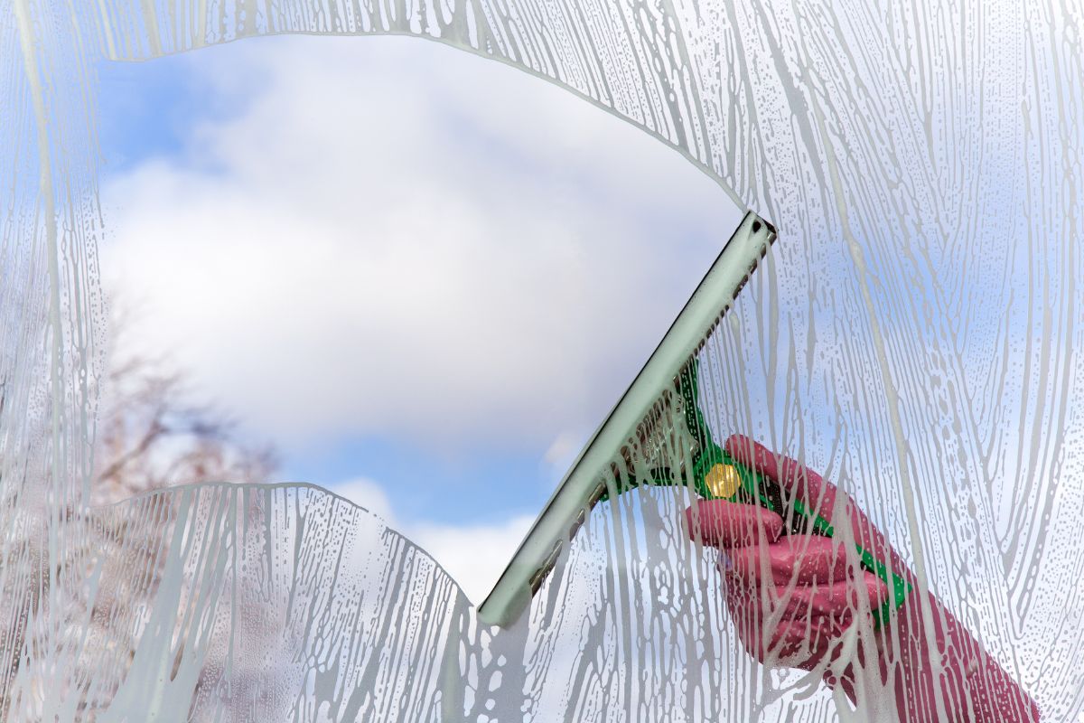 A person using a squeegee to clean a large window, focusing on removing streaks for a clear view.